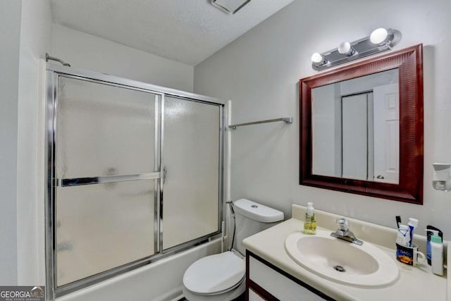 bathroom featuring vanity, toilet, combined bath / shower with glass door, and a textured ceiling