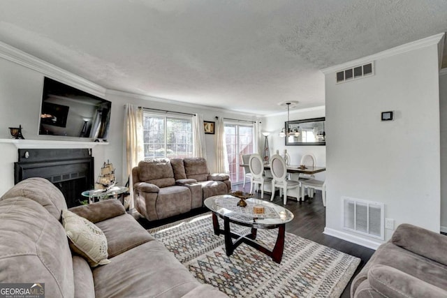 living area with wood finished floors, visible vents, and ornamental molding