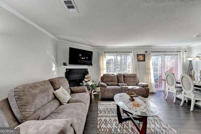 living area featuring dark wood finished floors, crown molding, a fireplace, and visible vents