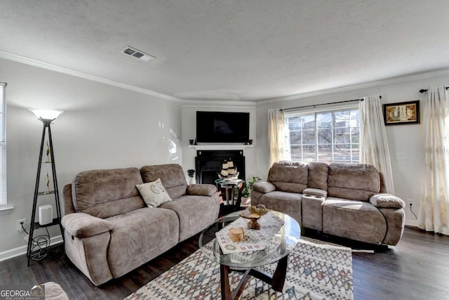 living room featuring visible vents, baseboards, a fireplace, dark wood-type flooring, and crown molding