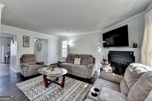 living room with visible vents, wood finished floors, a fireplace, and crown molding