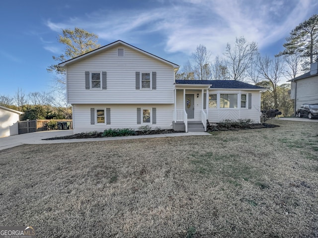 tri-level home with a front lawn and fence