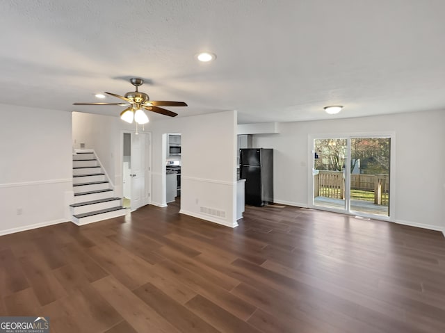 unfurnished living room with visible vents, a ceiling fan, dark wood-style floors, stairway, and baseboards