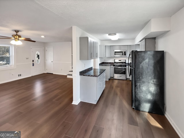 kitchen featuring gray cabinets, stainless steel appliances, baseboards, and dark wood-style flooring