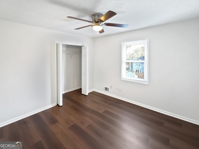 unfurnished bedroom with visible vents, ceiling fan, baseboards, a closet, and dark wood-style flooring