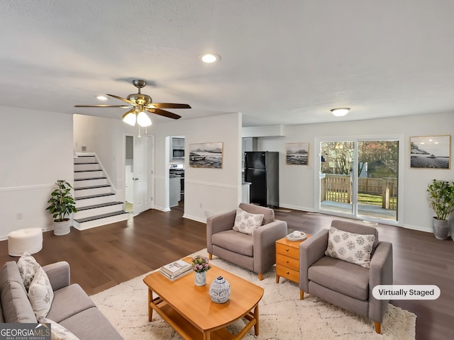 living room featuring stairway, baseboards, and wood finished floors