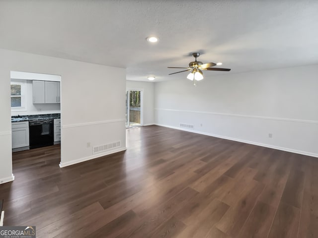 unfurnished living room with visible vents, dark wood-type flooring, and baseboards