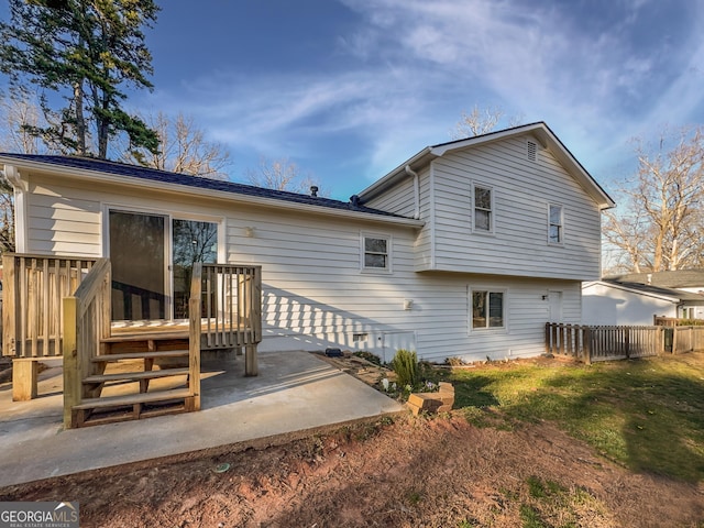 rear view of property featuring a lawn, a wooden deck, and fence