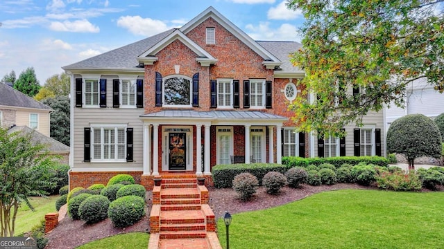 view of front of home with brick siding, a front lawn, and a shingled roof