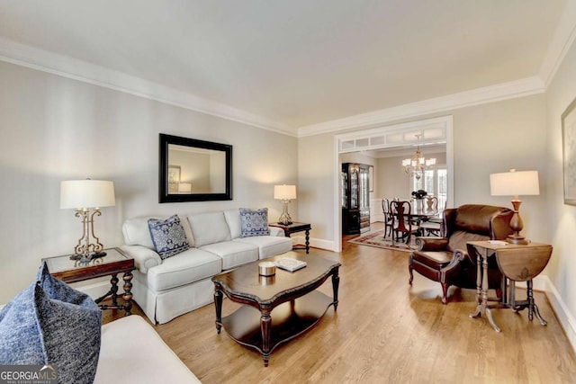 living area with baseboards, light wood-style floors, an inviting chandelier, and crown molding