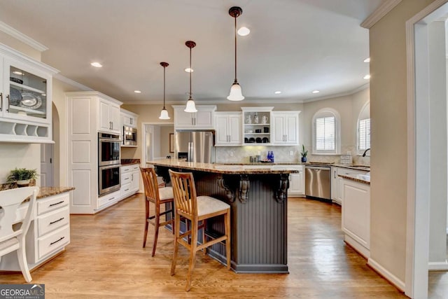 kitchen with stainless steel appliances, white cabinets, decorative backsplash, and light wood finished floors