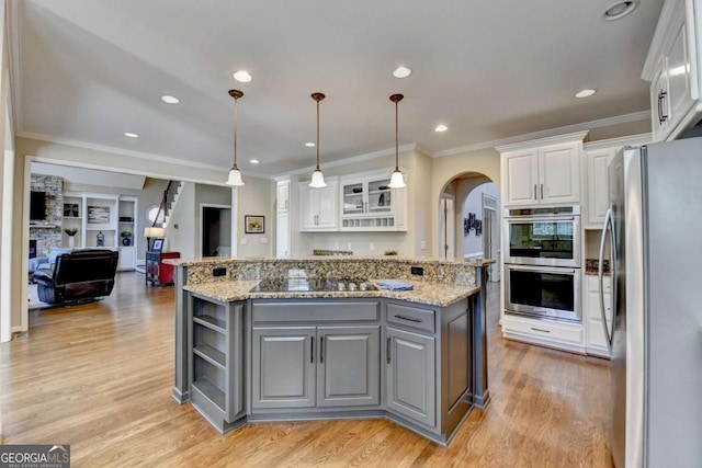 kitchen featuring a kitchen island, arched walkways, gray cabinetry, white cabinets, and appliances with stainless steel finishes