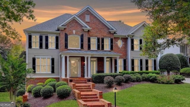 view of front of property featuring brick siding, roof with shingles, and a front lawn