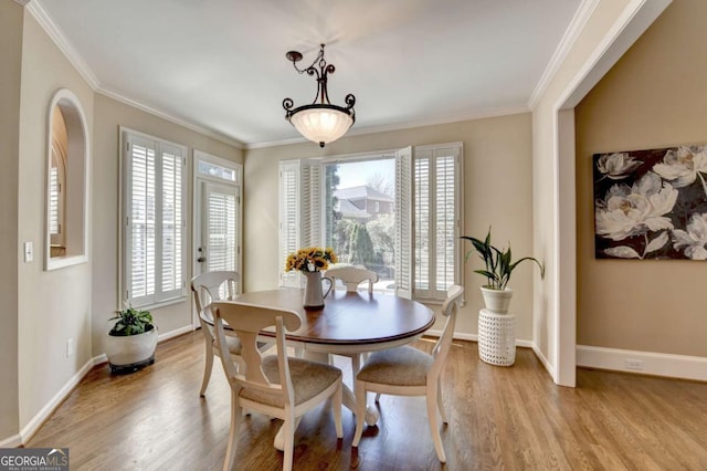 dining area with baseboards, wood finished floors, and ornamental molding