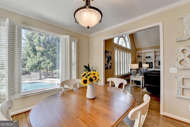 dining area with built in shelves, baseboards, wood finished floors, and crown molding