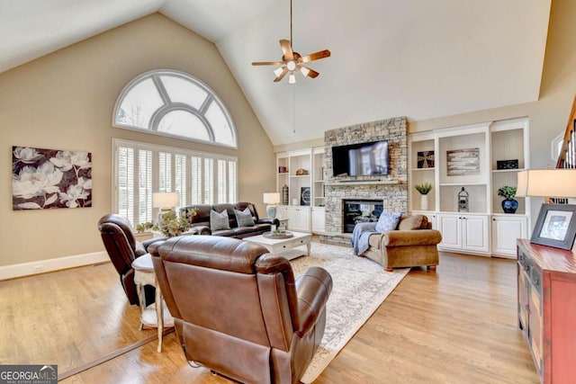 living area with a ceiling fan, baseboards, light wood finished floors, high vaulted ceiling, and a fireplace