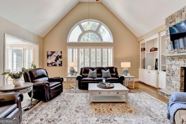 living room with a fireplace, plenty of natural light, wood finished floors, and high vaulted ceiling