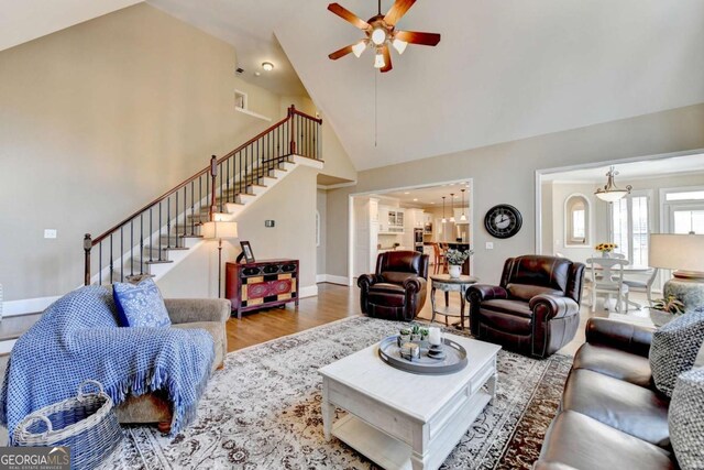 living area featuring stairway, high vaulted ceiling, ceiling fan, and wood finished floors