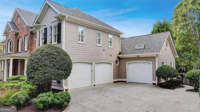 view of property exterior featuring concrete driveway and a shingled roof