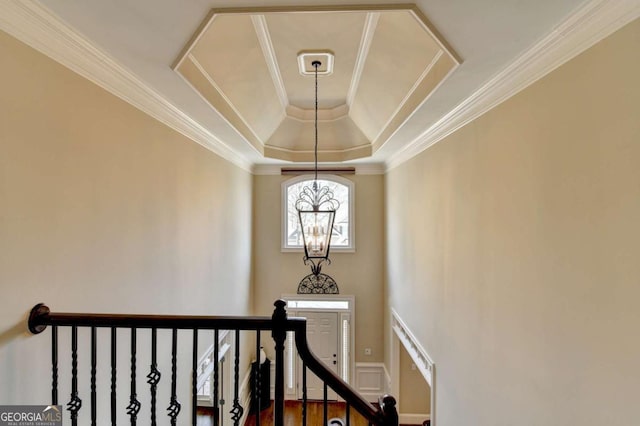 stairs featuring a raised ceiling, a notable chandelier, wood finished floors, and ornamental molding