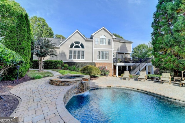 pool with stairs, an in ground hot tub, a patio area, and a wooden deck