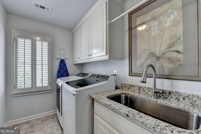 laundry room with visible vents, baseboards, washer and dryer, cabinet space, and a sink