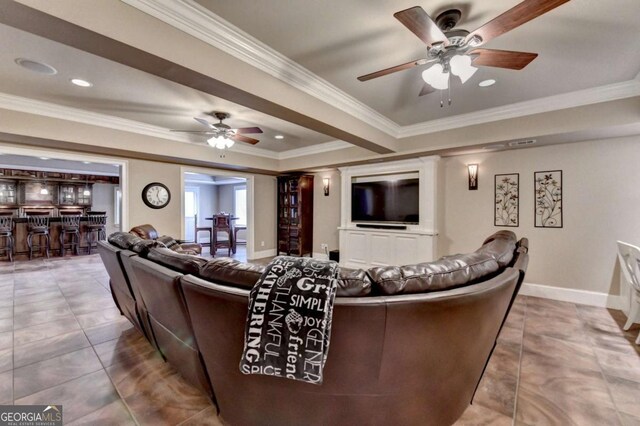 living area with a ceiling fan, baseboards, crown molding, tile patterned flooring, and bar area