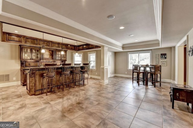 bar with a wealth of natural light, visible vents, a tray ceiling, and ornamental molding