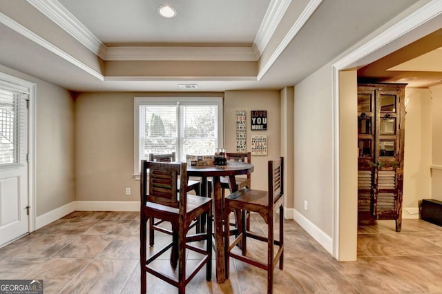 dining space featuring baseboards, a raised ceiling, and crown molding