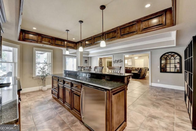 kitchen with a kitchen island, baseboards, pendant lighting, a tray ceiling, and fridge