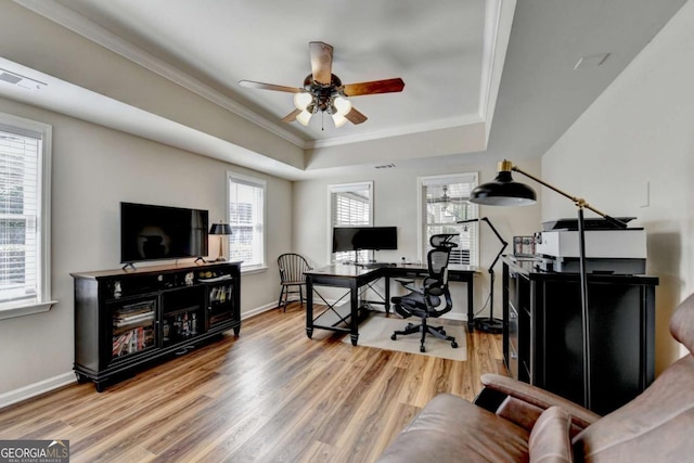 home office featuring baseboards, a raised ceiling, wood finished floors, and ornamental molding