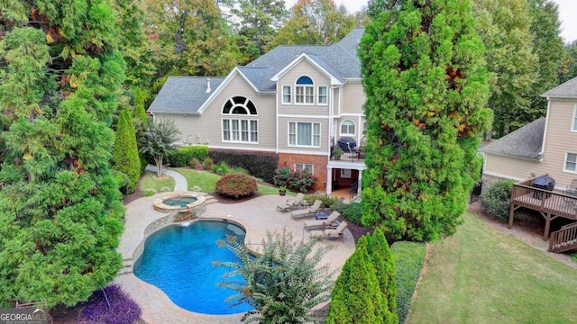 rear view of house with a patio, a yard, a shingled roof, an outdoor pool, and an in ground hot tub