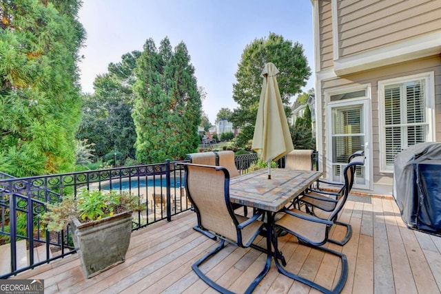 deck with a fenced in pool, a grill, and outdoor dining area