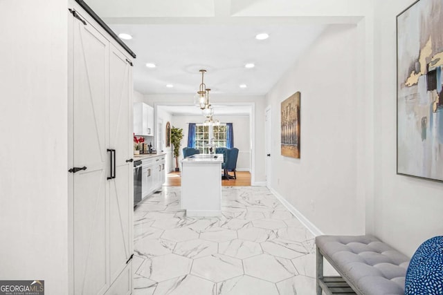 interior space with a center island, baseboards, pendant lighting, marble finish floor, and white cabinetry