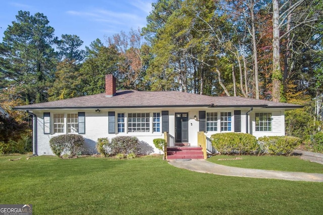 ranch-style house featuring a front yard, brick siding, and a chimney