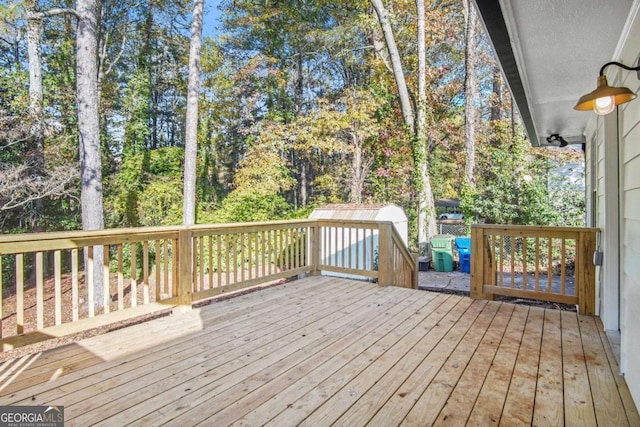 wooden terrace featuring a shed and an outdoor structure