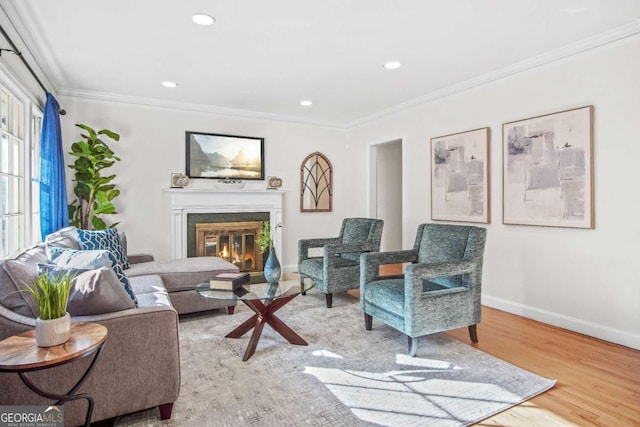 living room featuring a glass covered fireplace, crown molding, baseboards, and wood finished floors