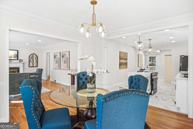 dining area with baseboards, a notable chandelier, ornamental molding, and a fireplace