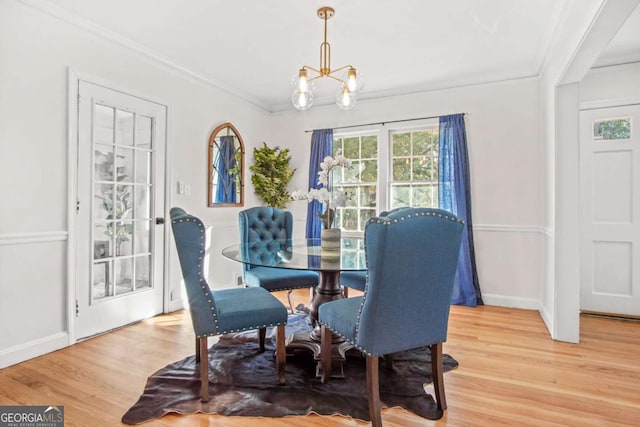 dining room with baseboards, an inviting chandelier, ornamental molding, and light wood finished floors