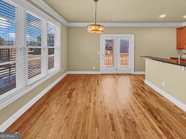 unfurnished dining area featuring visible vents, baseboards, light wood finished floors, and ornamental molding