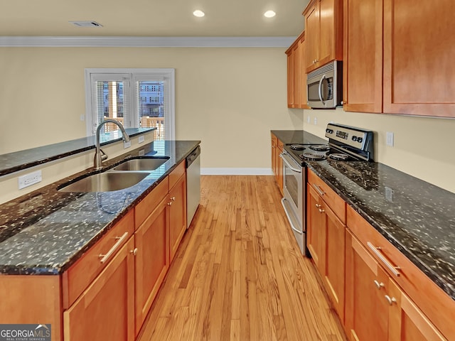 kitchen featuring visible vents, a sink, stainless steel appliances, crown molding, and light wood-type flooring