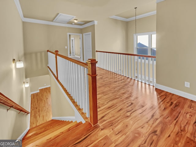 staircase with ornamental molding, attic access, baseboards, and wood finished floors