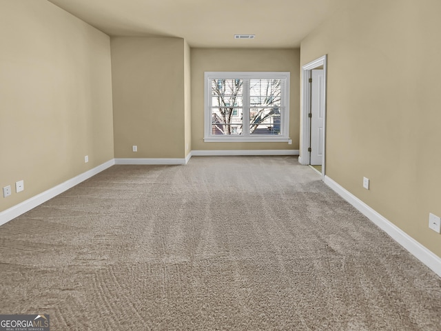 empty room featuring carpet flooring, visible vents, and baseboards