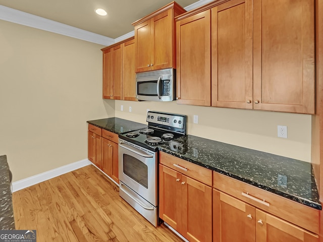 kitchen featuring stainless steel appliances, light wood-type flooring, dark stone counters, and ornamental molding