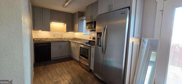 kitchen featuring a sink, dark wood-type flooring, appliances with stainless steel finishes, a textured wall, and a wealth of natural light