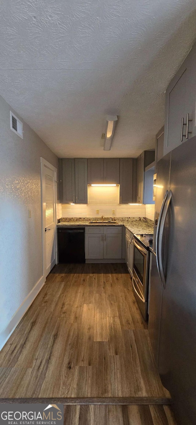 kitchen with visible vents, gray cabinetry, dark wood finished floors, light countertops, and appliances with stainless steel finishes