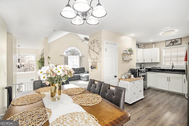 dining room featuring ceiling fan with notable chandelier, lofted ceiling, and wood finished floors