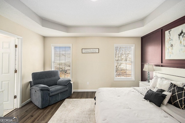 bedroom with dark wood-type flooring, baseboards, and a raised ceiling