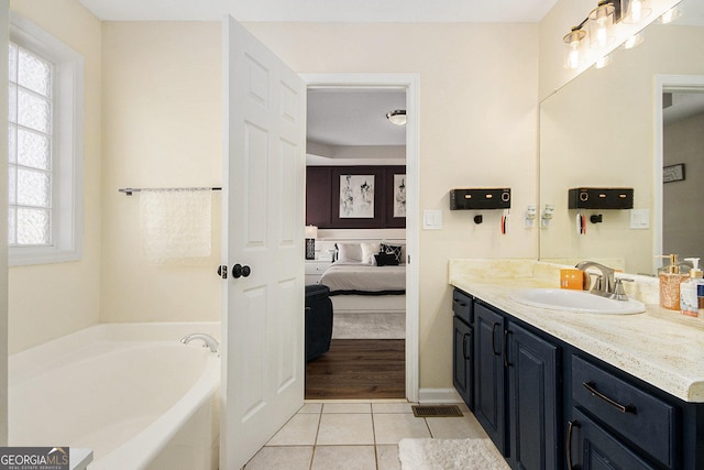 ensuite bathroom with tile patterned flooring, connected bathroom, vanity, and a garden tub