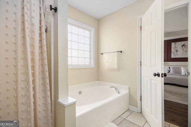 ensuite bathroom featuring tile patterned floors, connected bathroom, a garden tub, and a shower with shower curtain